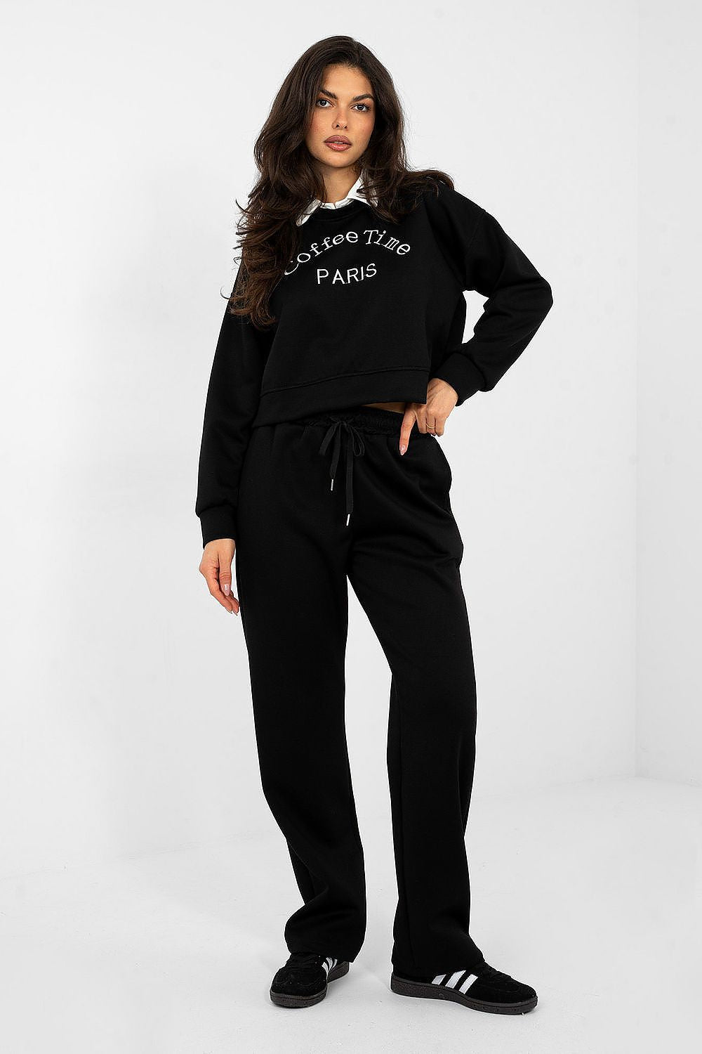 Woman wearing a black tracksuit with text on the hoodie against a white background