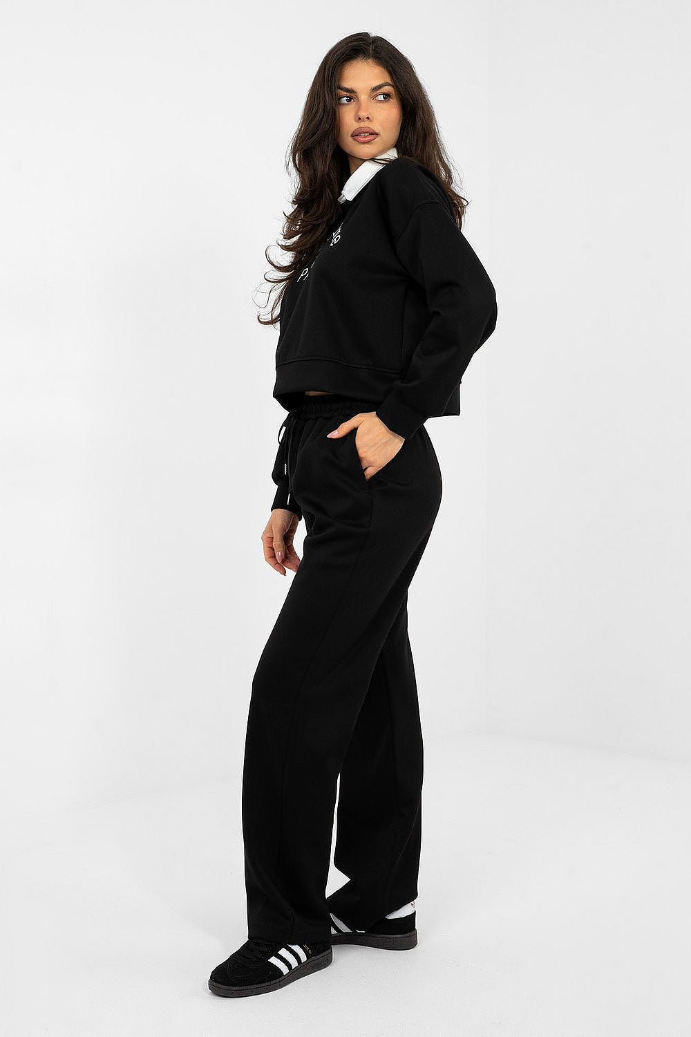 Woman wearing a black tracksuit with white stripes on a white background