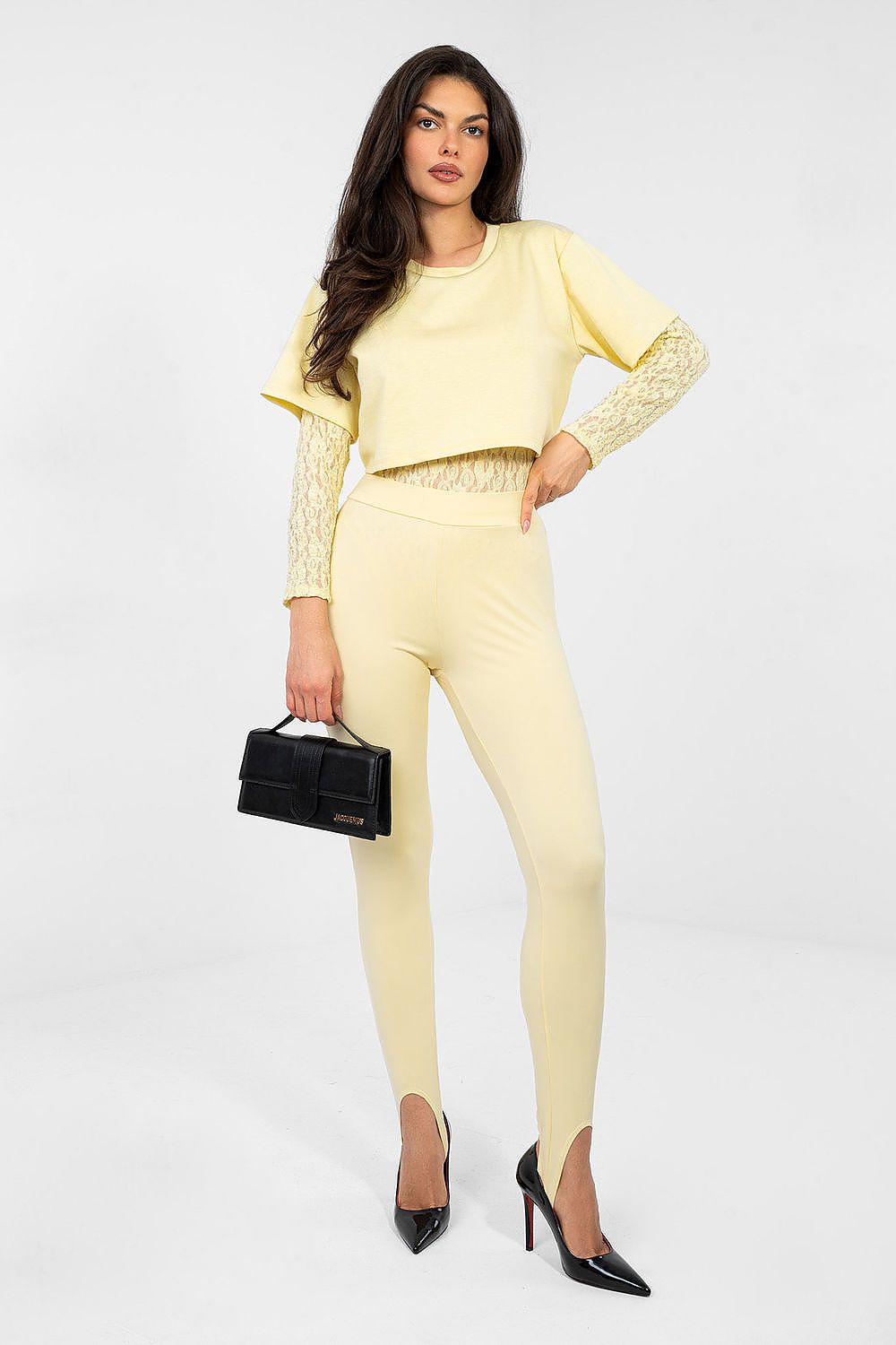 Woman wearing a yellow outfit with a black handbag on a white background