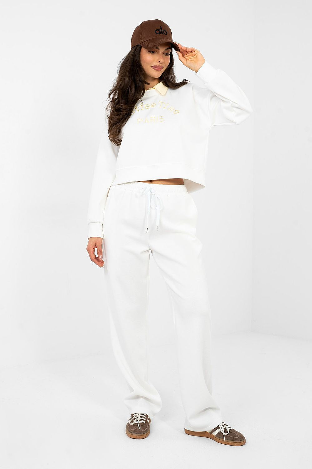 Woman wearing a white outfit with a brown cap on a white background