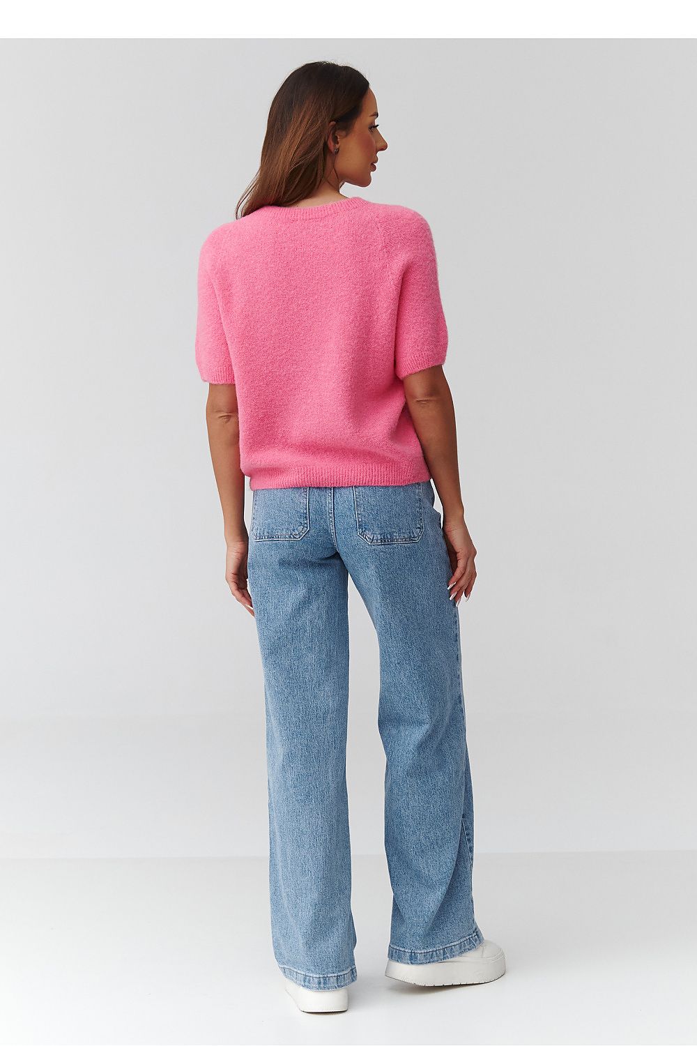 Person wearing a pink sweater and blue jeans on a white background