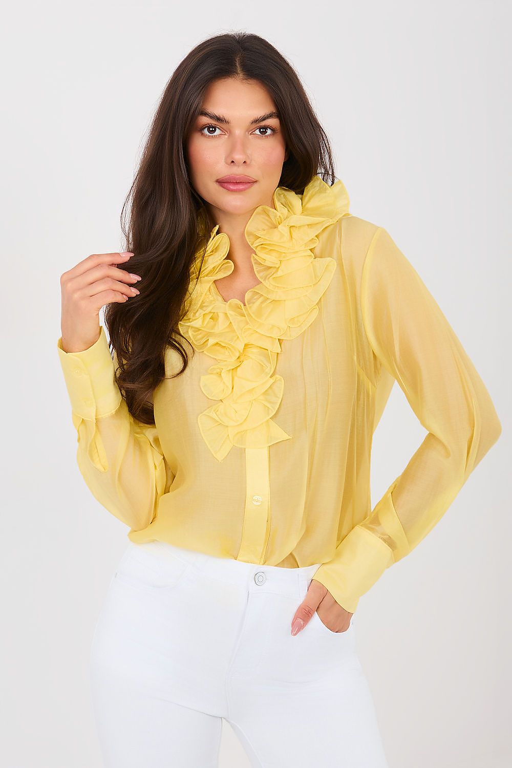 Woman wearing a yellow ruffled blouse against a white background