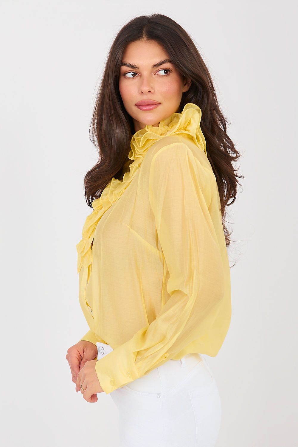 Woman wearing a yellow blouse with ruffled details on a white background
