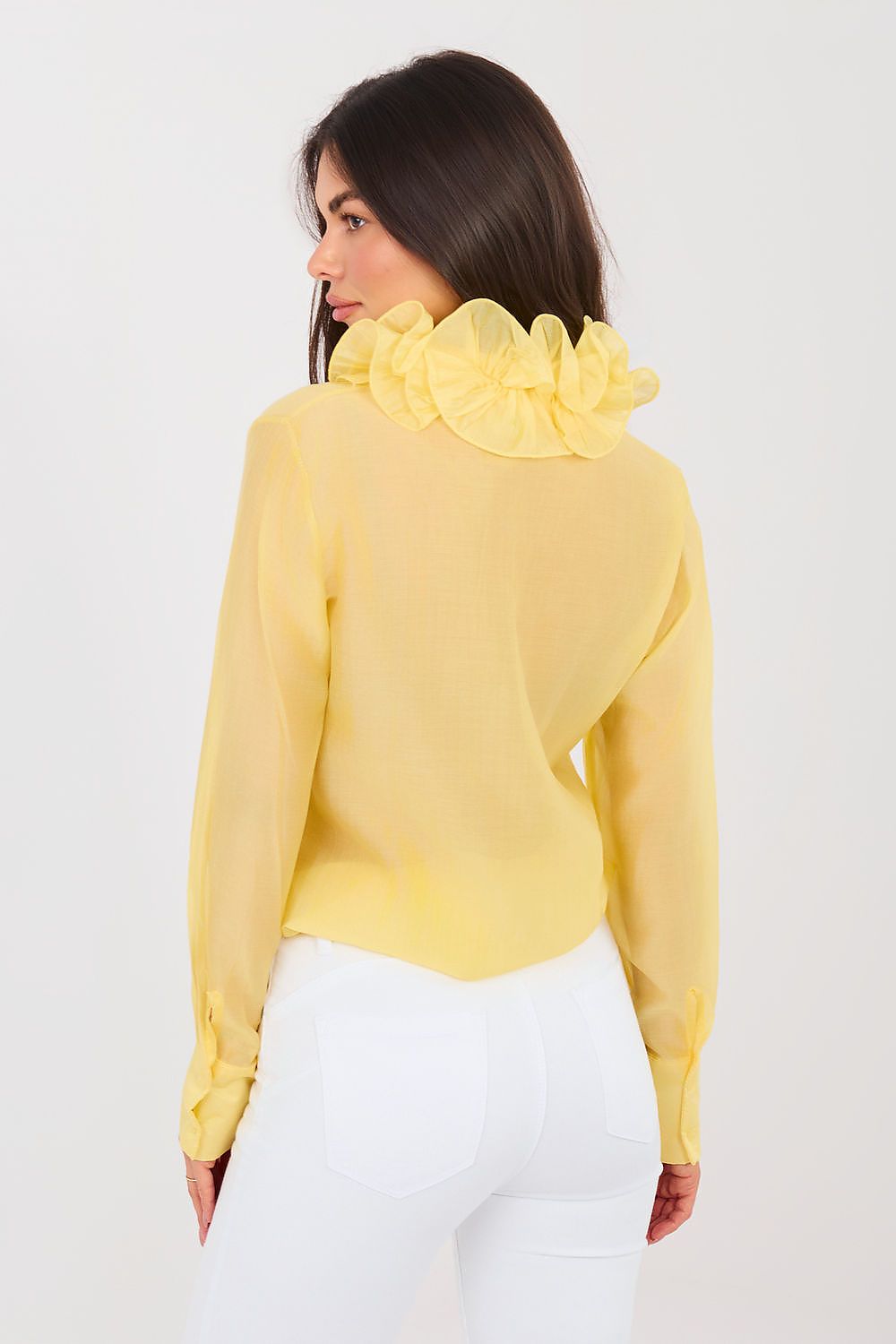 Woman wearing a yellow blouse with a ruffled collar on a white background