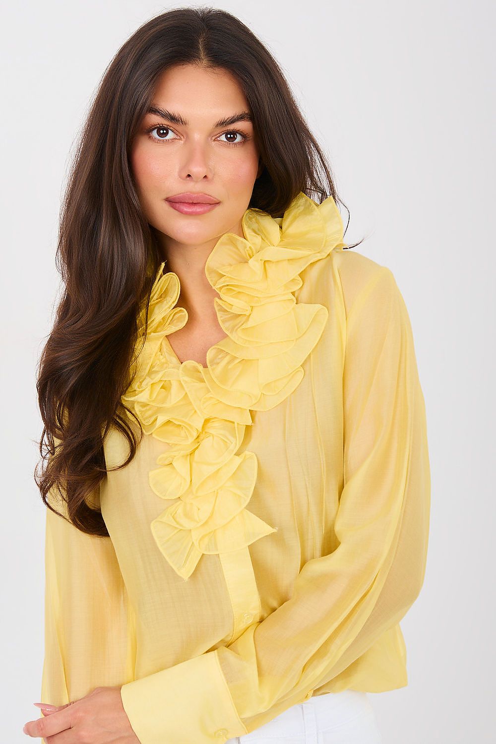 Woman wearing a yellow ruffled blouse against a white background