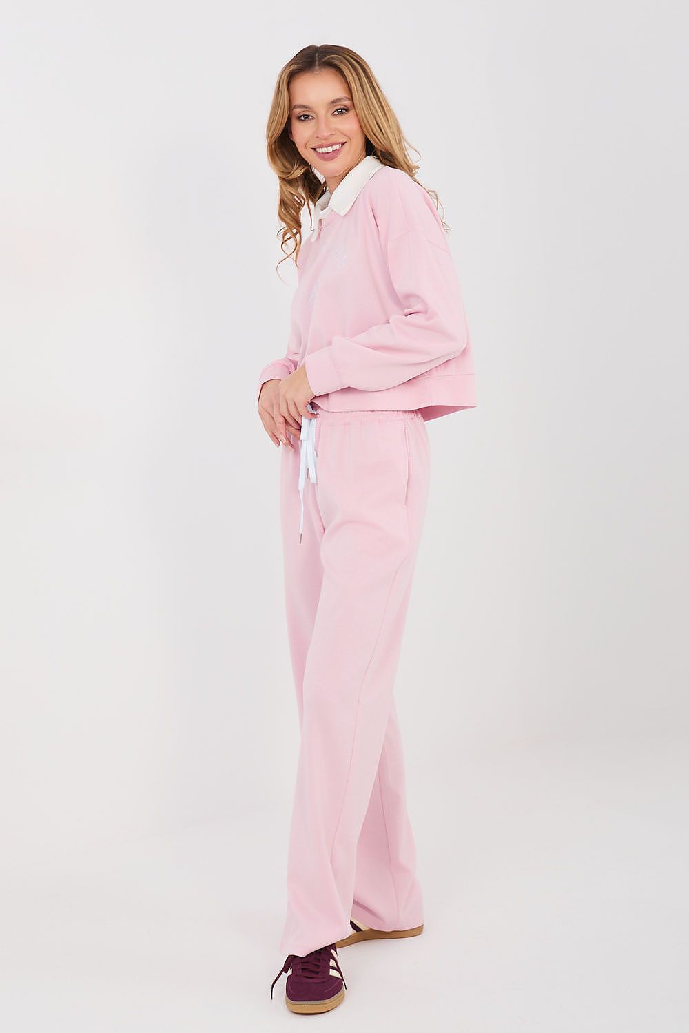 Woman wearing a pink tracksuit on a white background