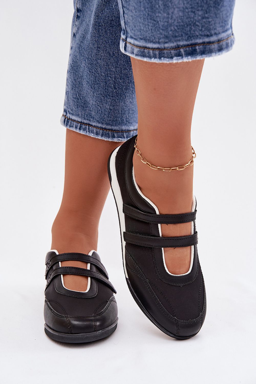 Black shoes with white soles worn by a person on a white background