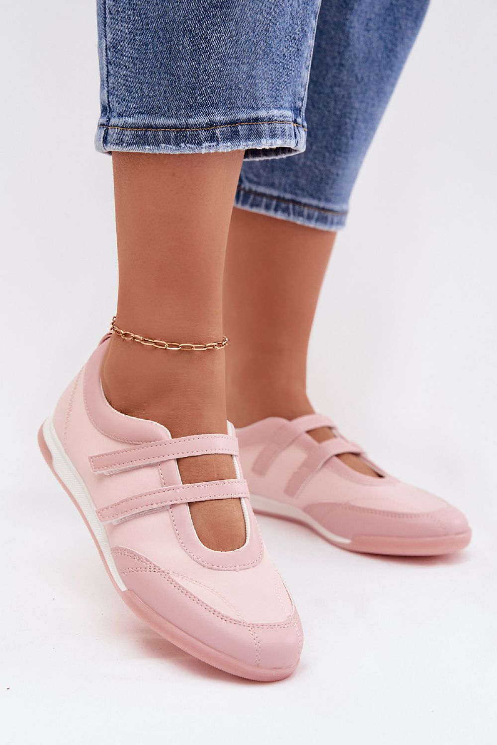 Pink shoes worn with blue jeans on a white background