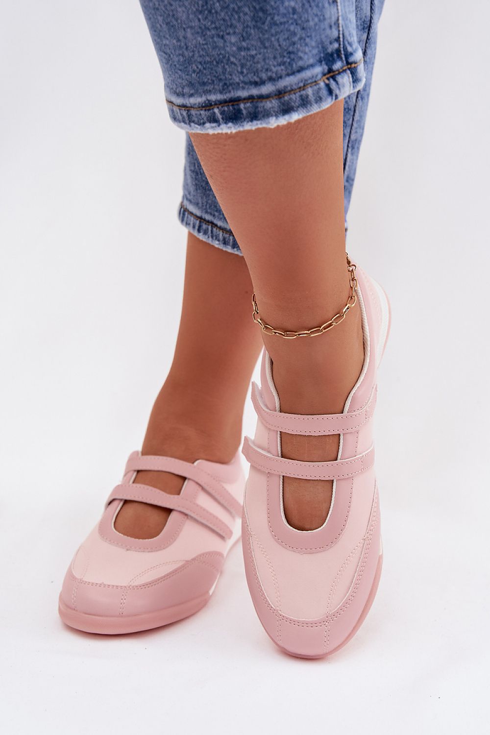 Pink flat shoes worn with denim jeans on a white background