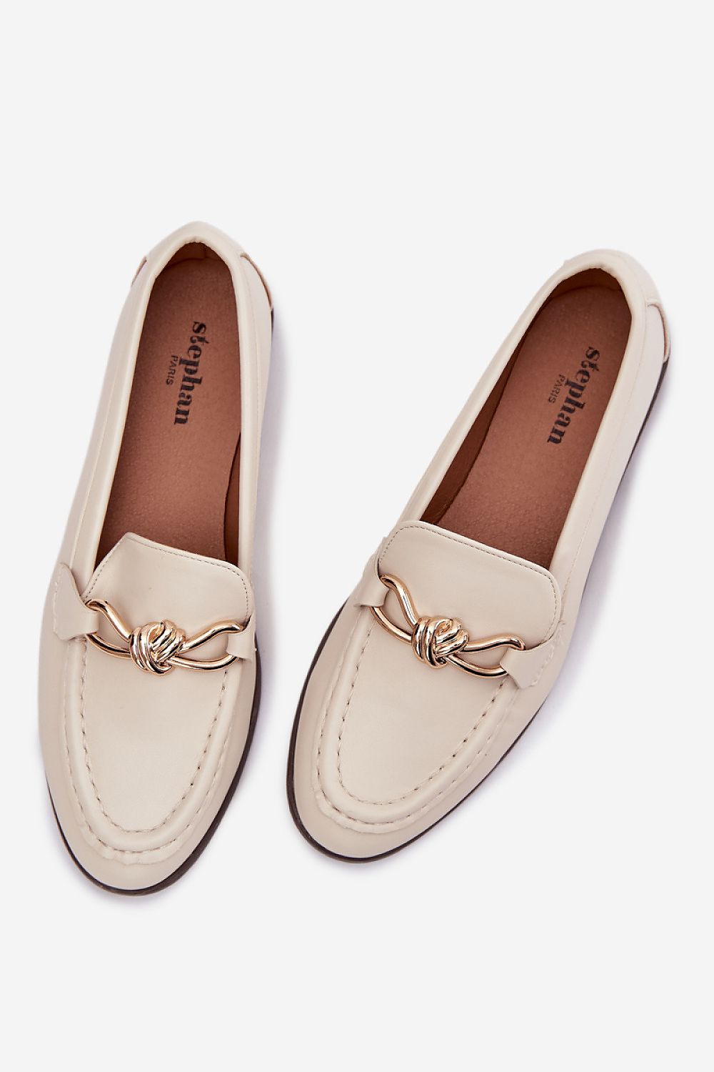 Pair of cream loafers with a decorative bow on a white background