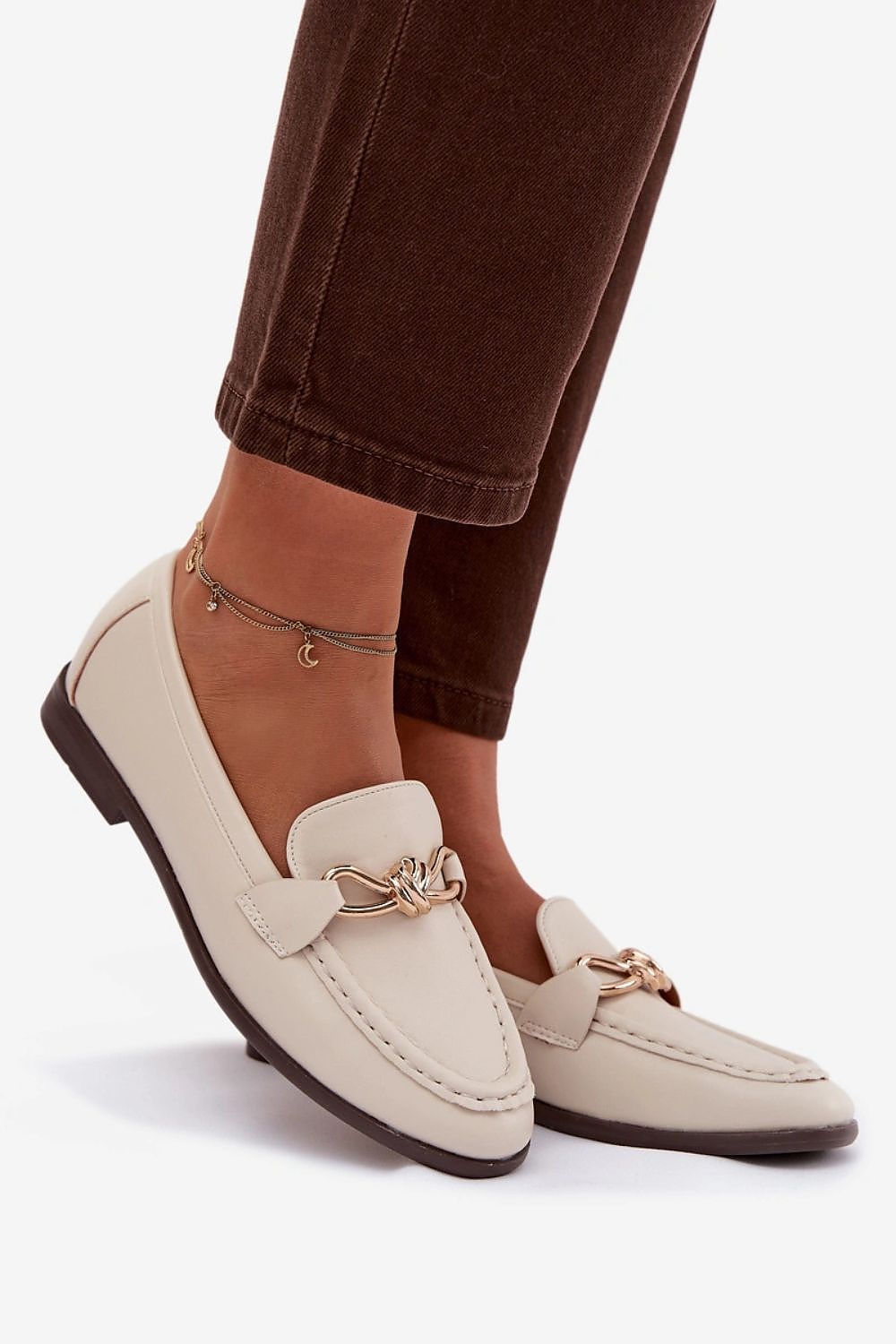 Beige loafers worn with brown pants on a white background