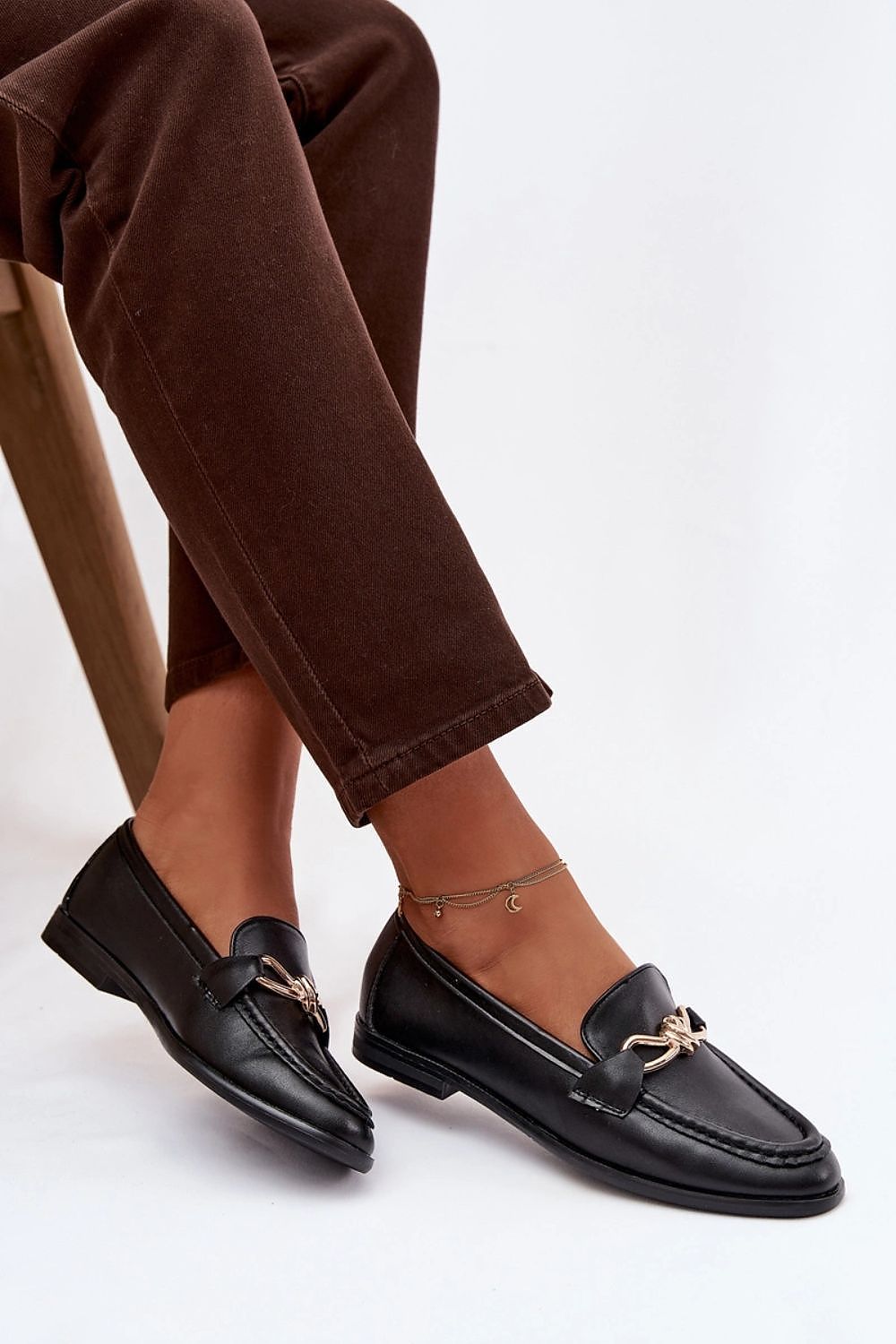 Black loafers worn with brown pants on a white background