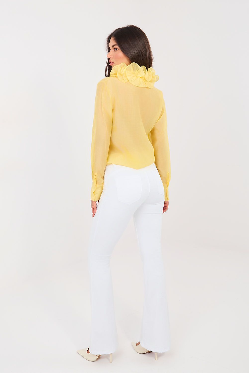 Woman wearing a yellow blouse and white pants on a white background