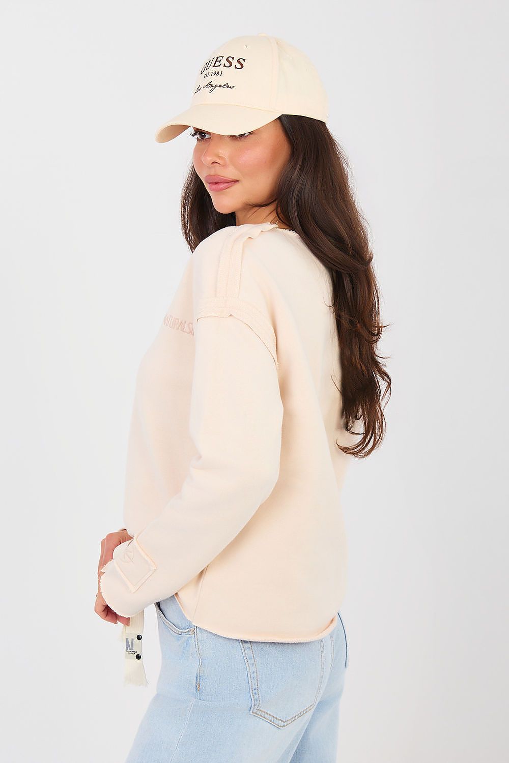 Woman wearing a beige sweater and cap with a plain background