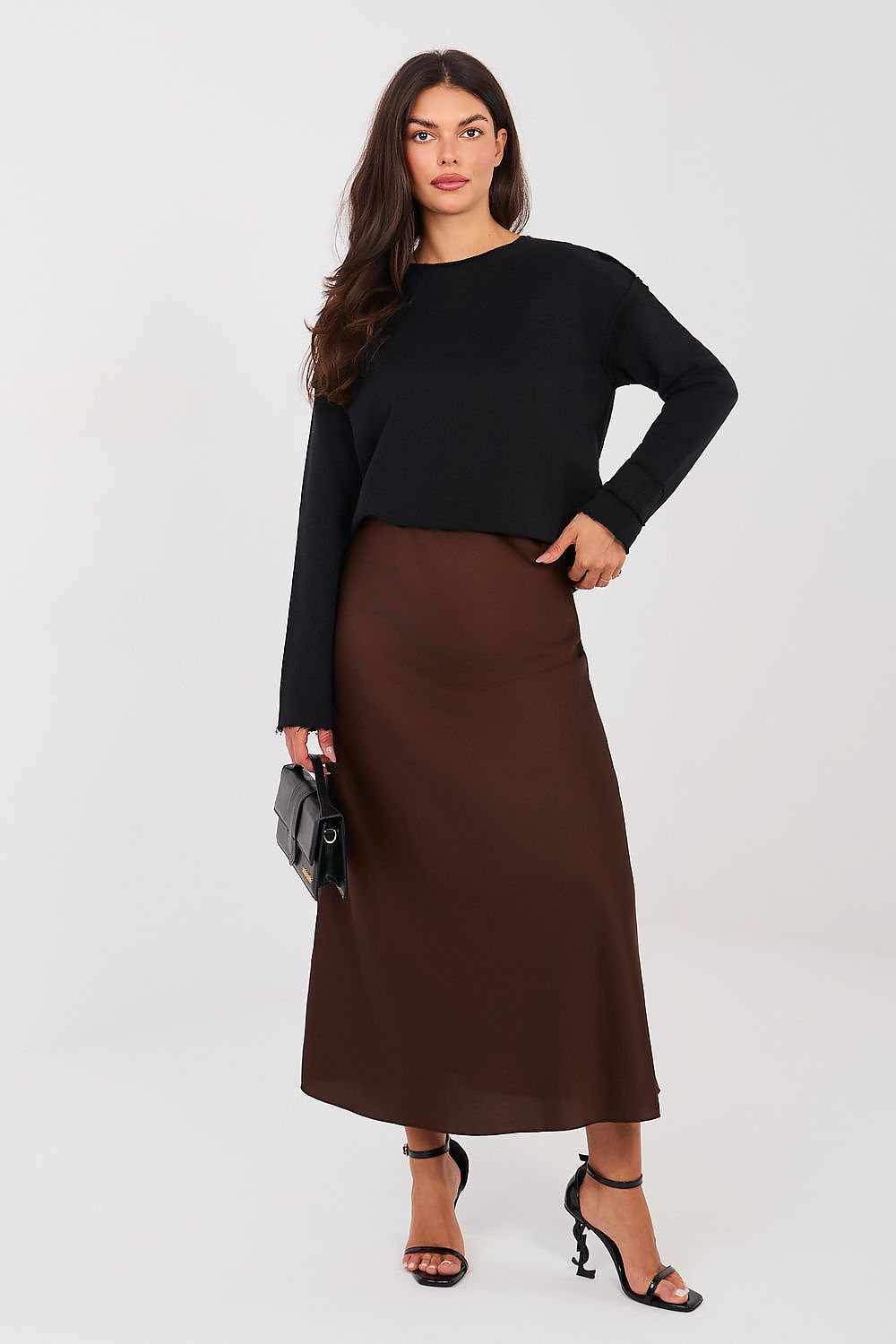 Woman wearing a black top and brown skirt on a white background