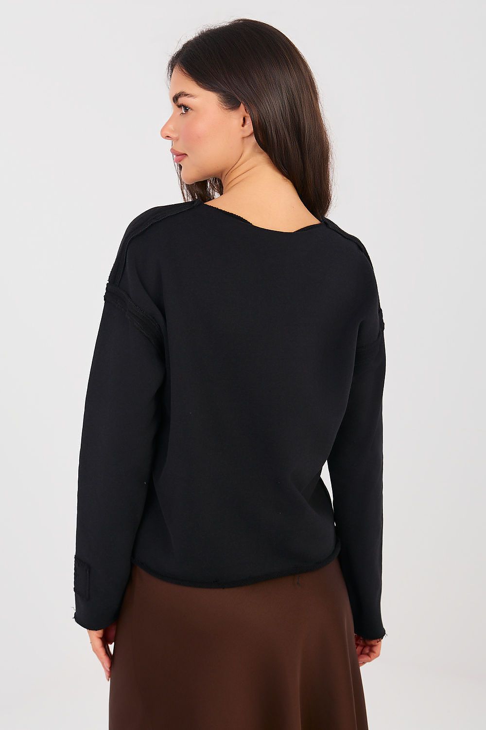 Woman wearing a black long-sleeve top and brown skirt on a white background