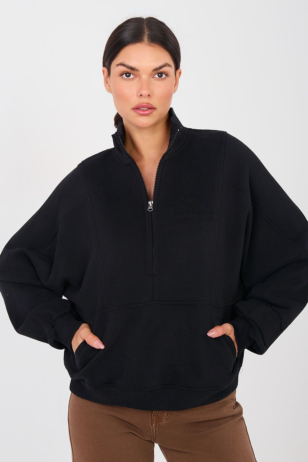 Woman wearing a black half-zip sweatshirt against a white background