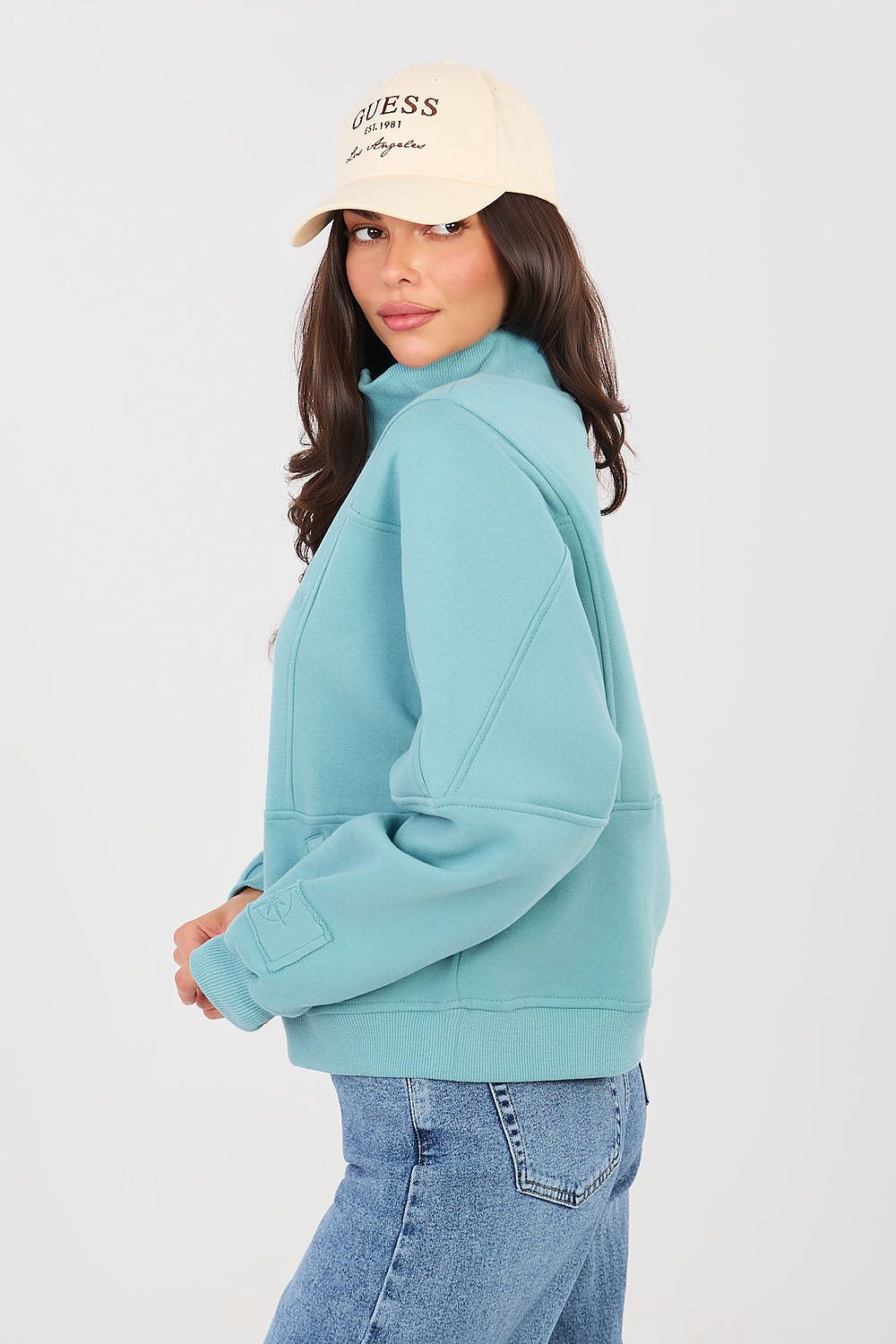 Woman wearing a light blue hoodie and beige cap on a white background