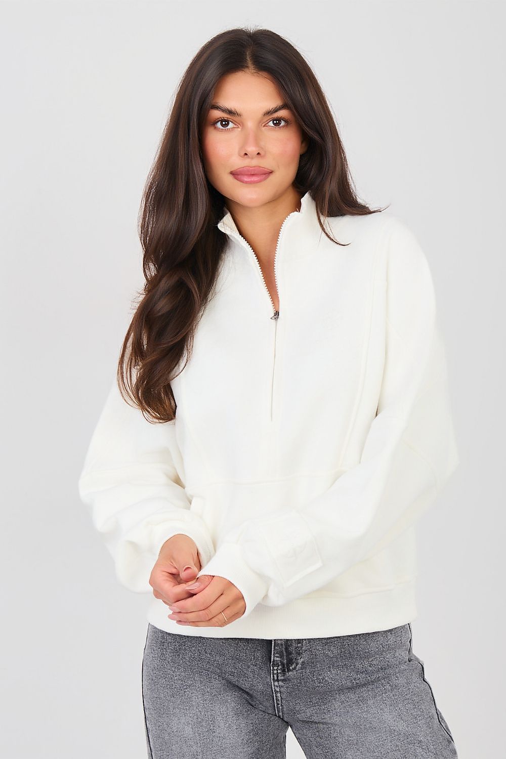 Woman wearing a white zip-up sweatshirt against a plain background