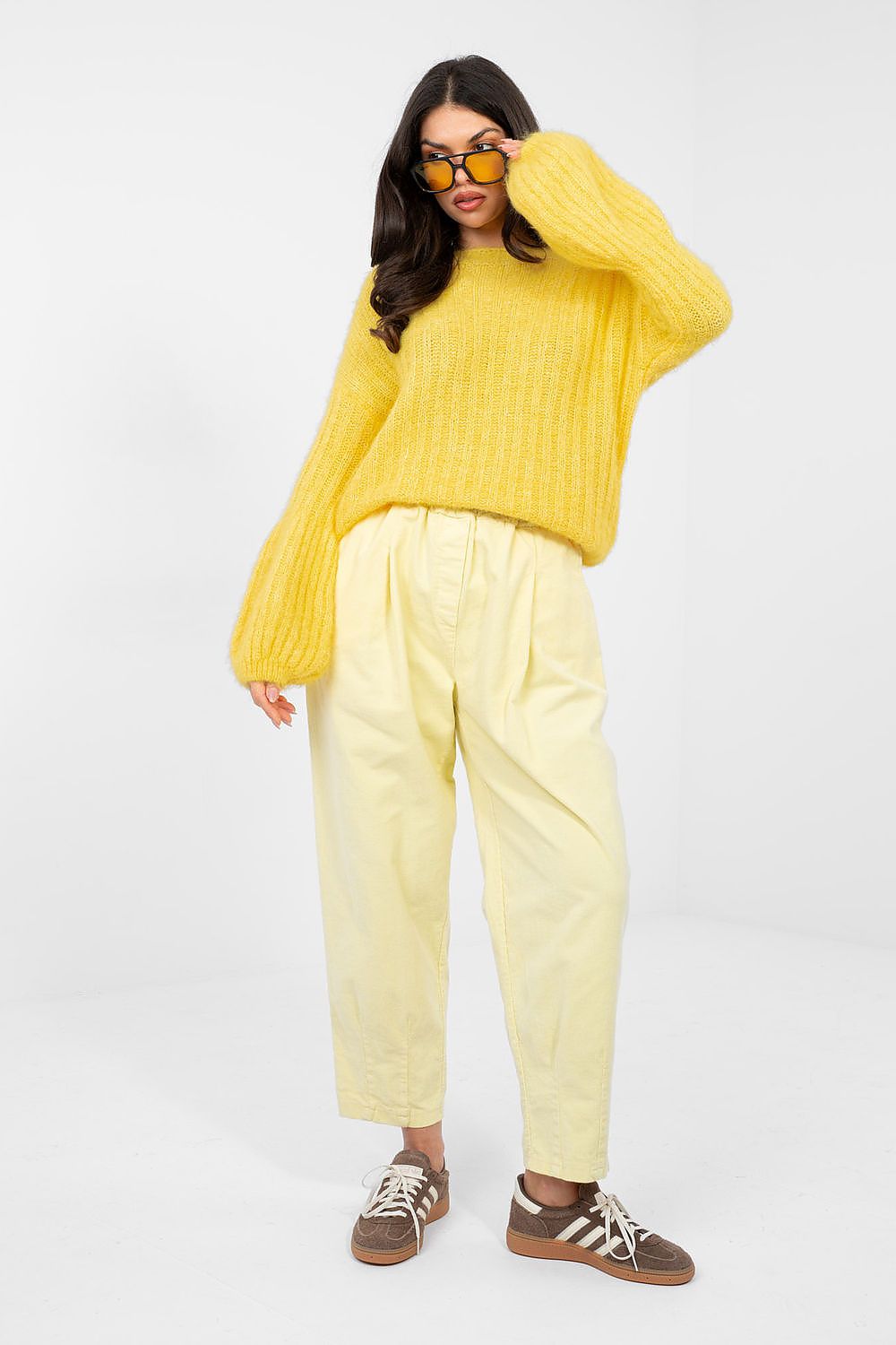 Person wearing a yellow sweater and pants on a white background