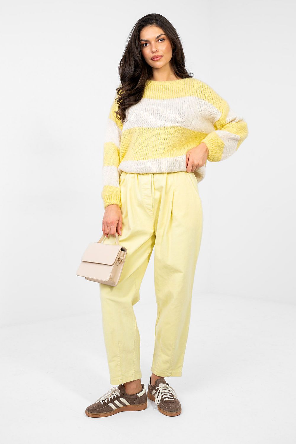 Woman wearing a yellow and white striped sweater with matching pants on a white background