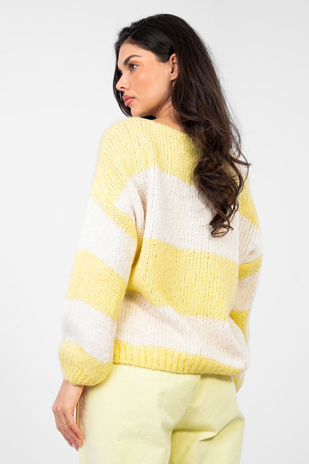 Woman wearing a yellow and white striped sweater against a white background