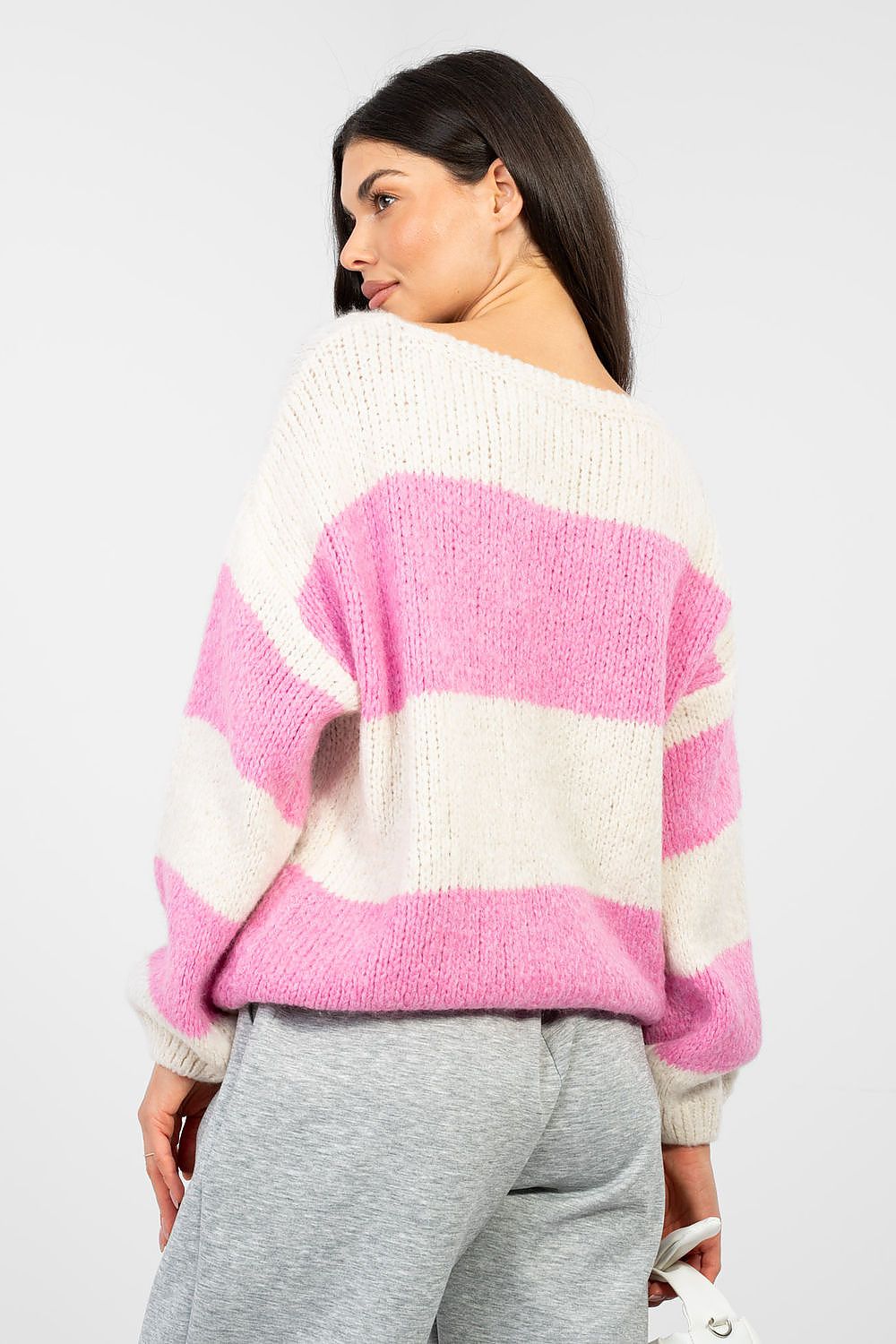 Woman wearing a pink and white striped sweater on a plain background
