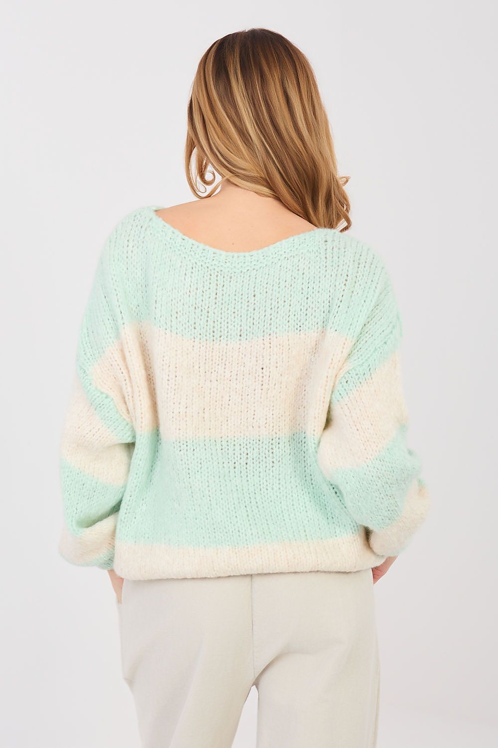 Person wearing a light green and white striped sweater on a plain background