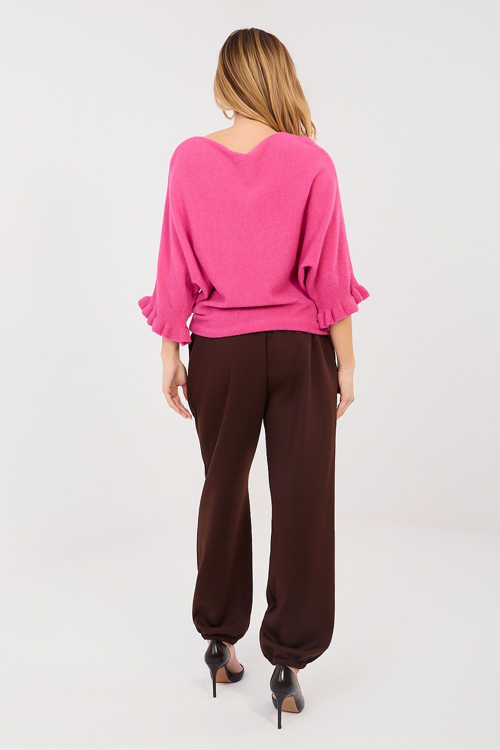 Person wearing a pink top and brown pants on a white background