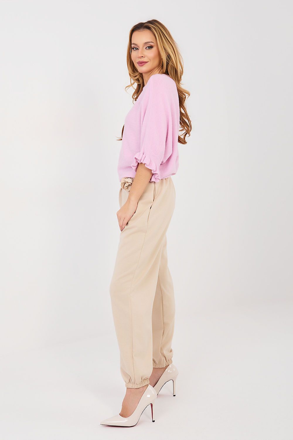 Woman wearing a pink blouse and beige pants on a white background