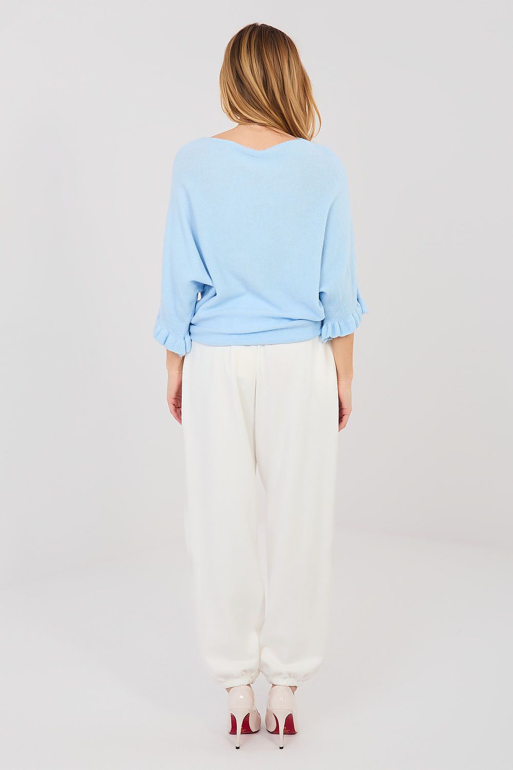 Person wearing a light blue top and white pants on a plain background