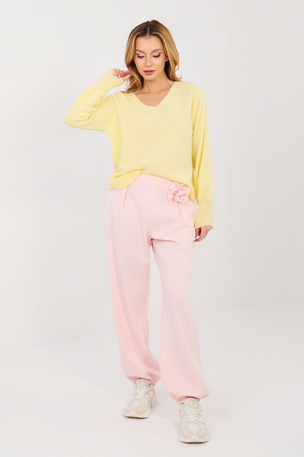 Woman wearing a yellow top and pink pants on a white background