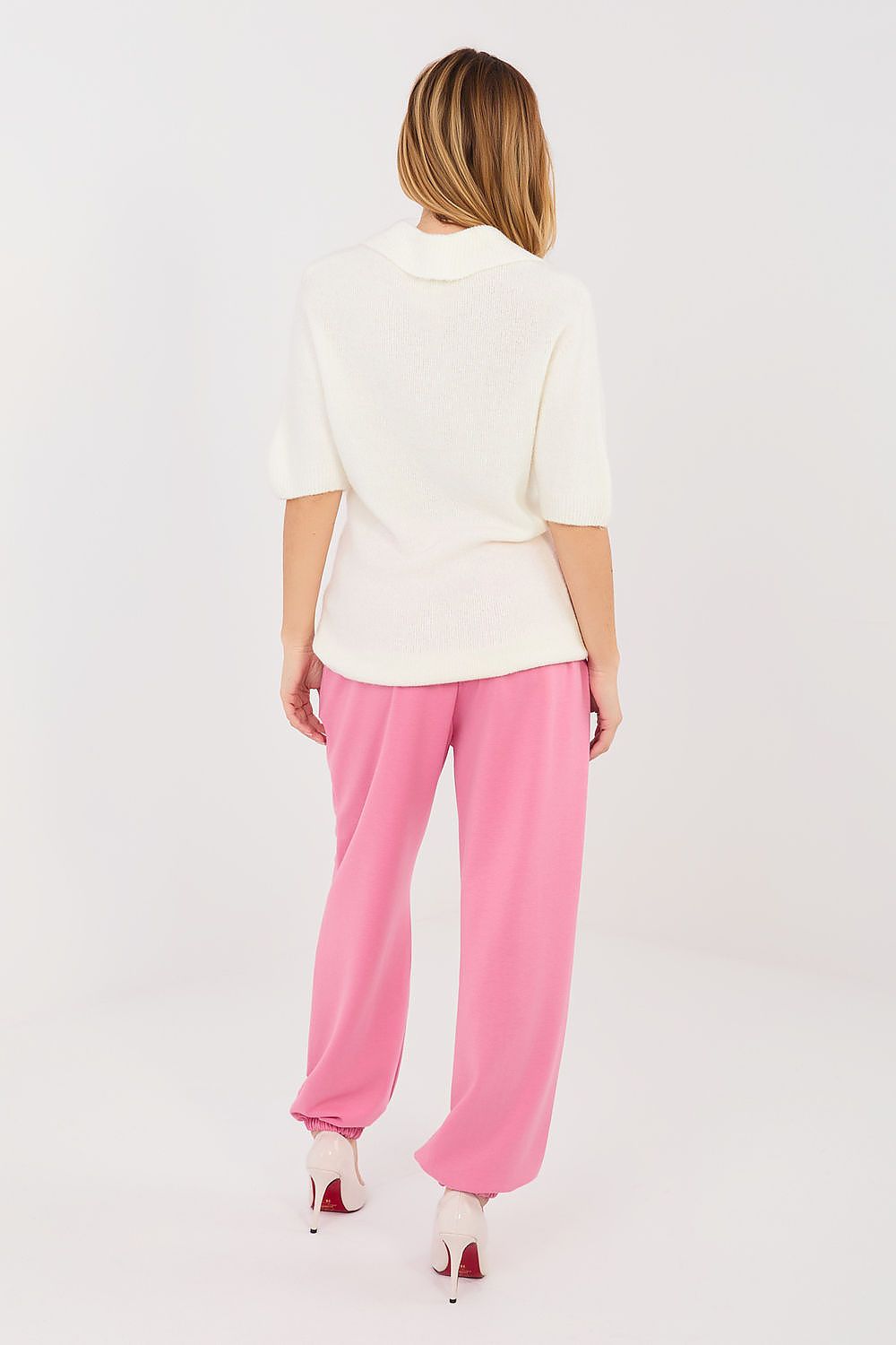 Woman wearing a white top and pink pants on a white background
