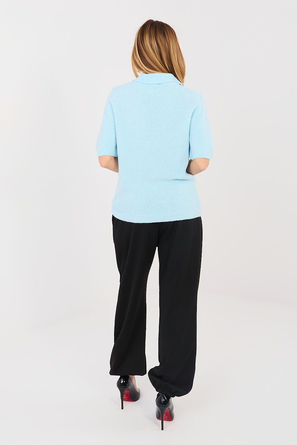 Person wearing a light blue polo shirt and black pants on a white background