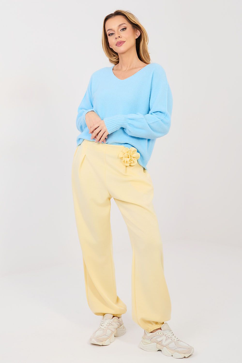 Woman wearing a light blue sweater and yellow pants on a white background