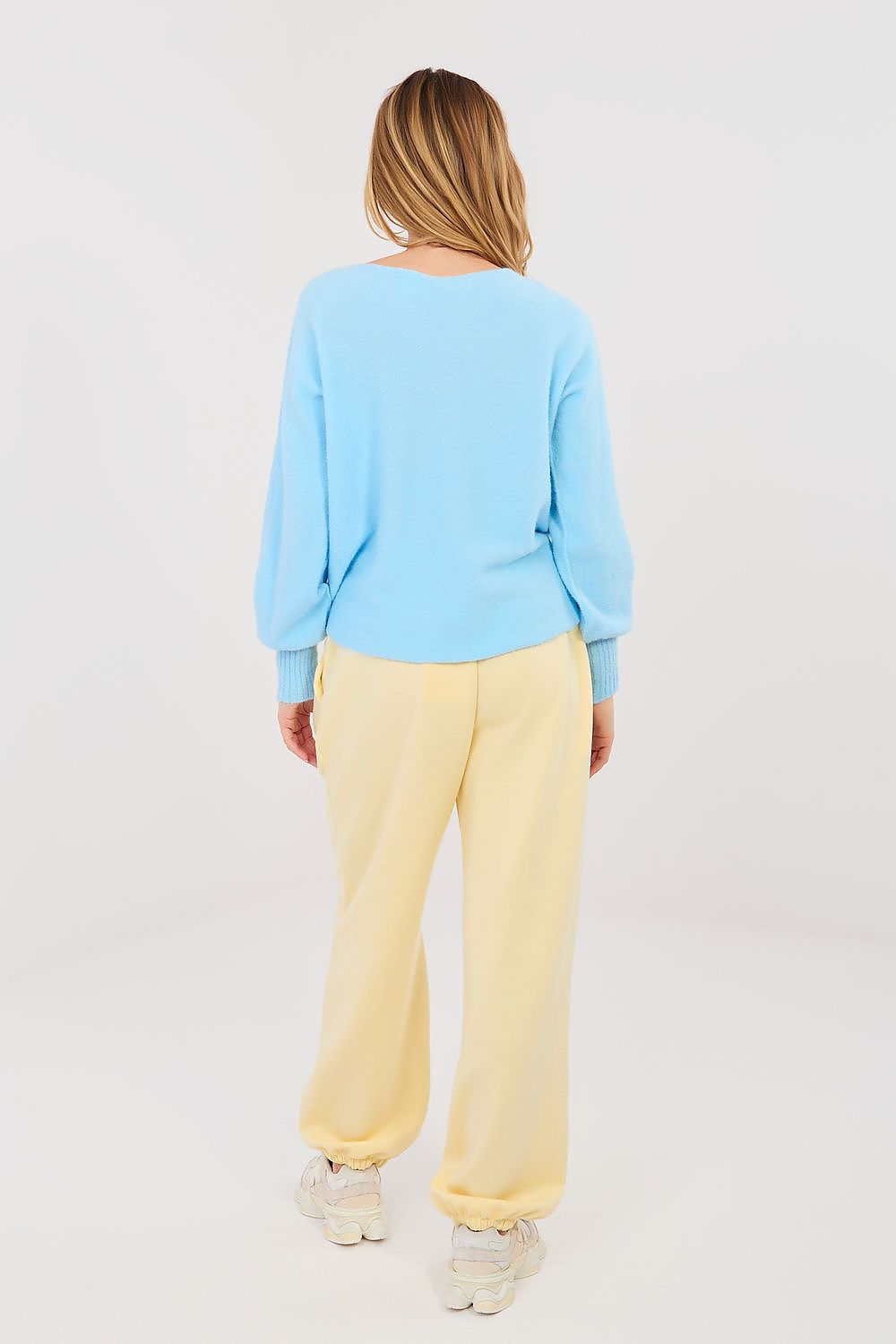 Woman wearing a light blue top and yellow pants on a white background