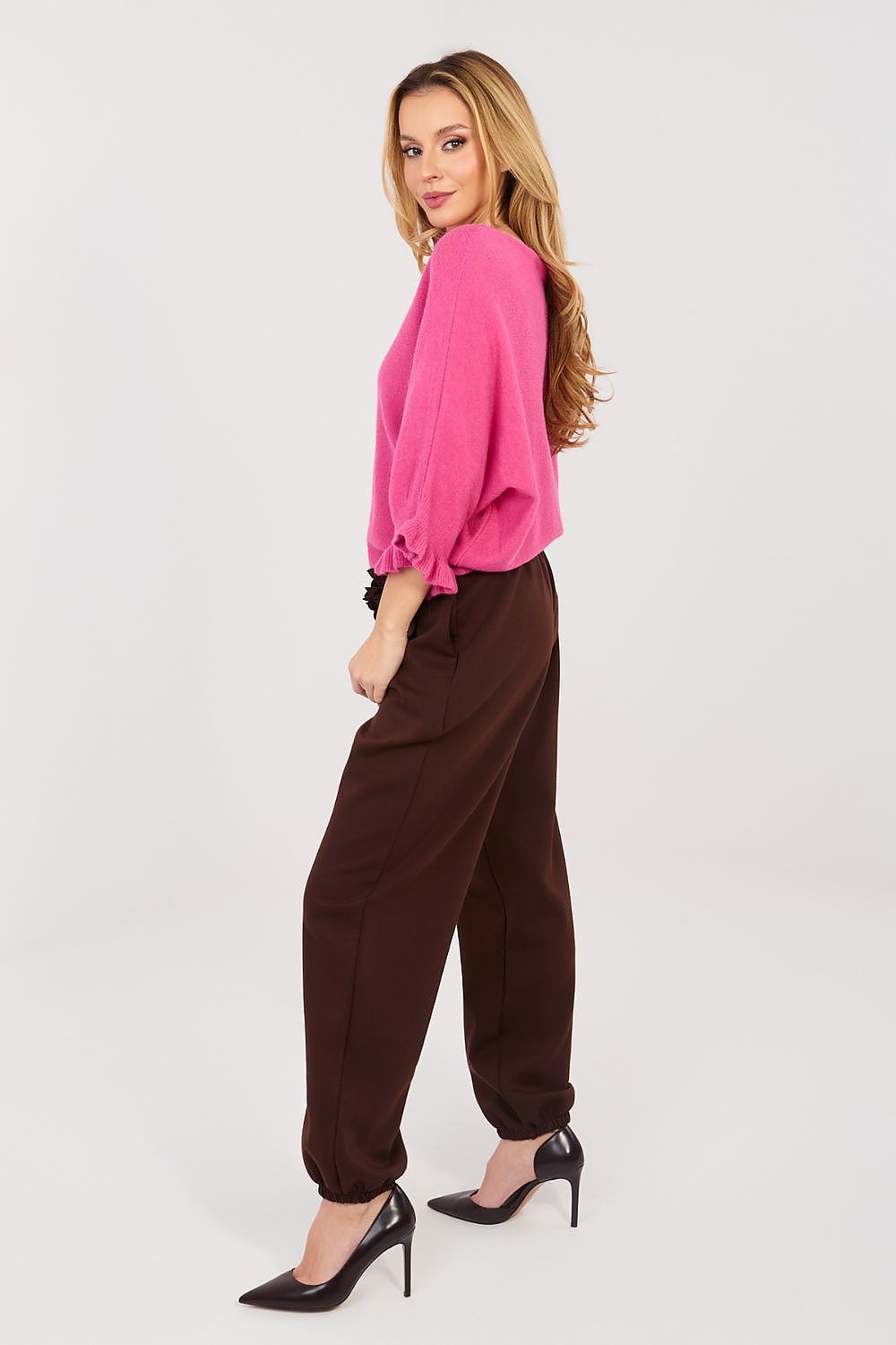 Woman wearing a pink blouse and brown pants on a white background