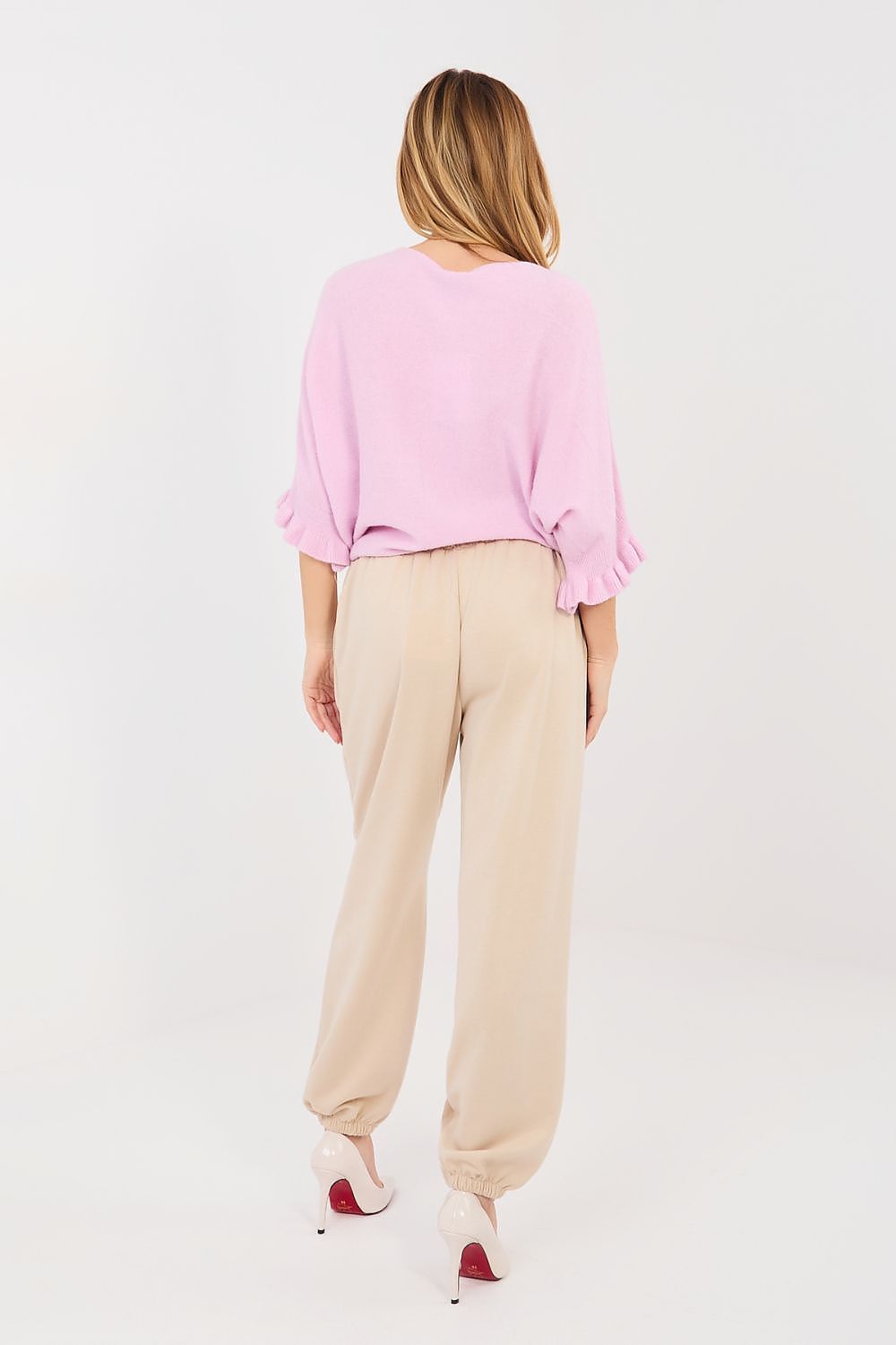 Woman wearing a pink top and beige pants on a white background