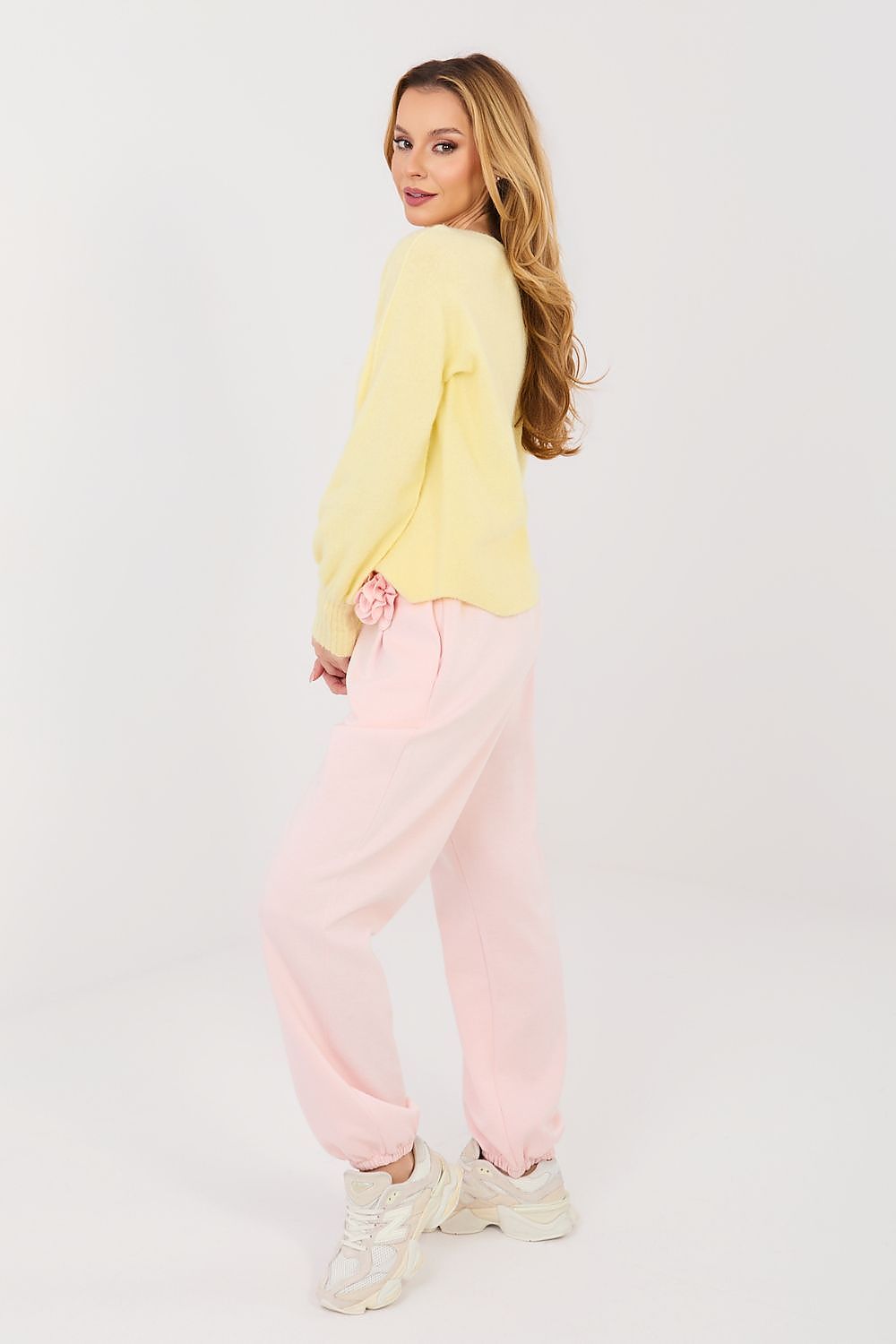 Woman wearing a yellow top and pink pants on a white background