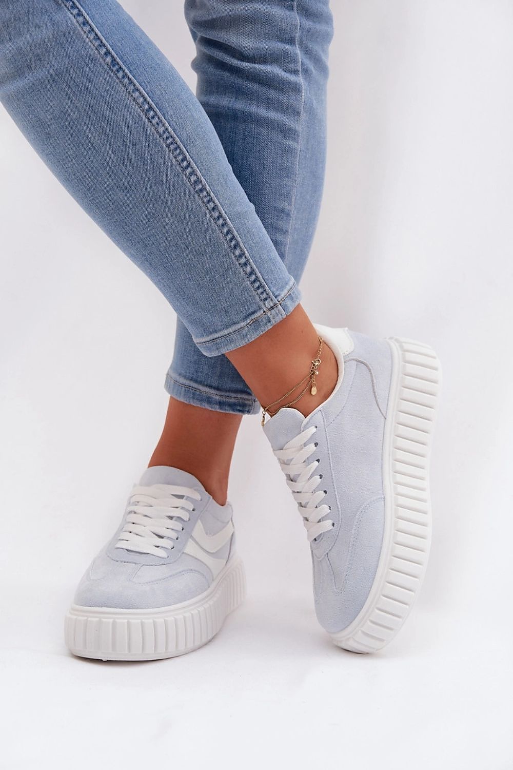 Light blue sneakers worn with light blue jeans on a white background