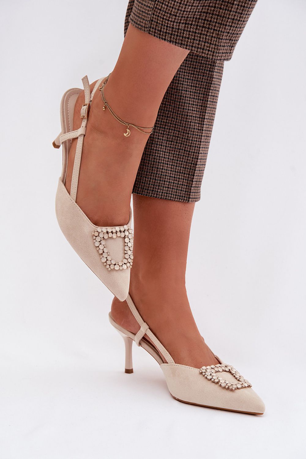 Beige high-heeled shoes with pearl embellishments on a white background