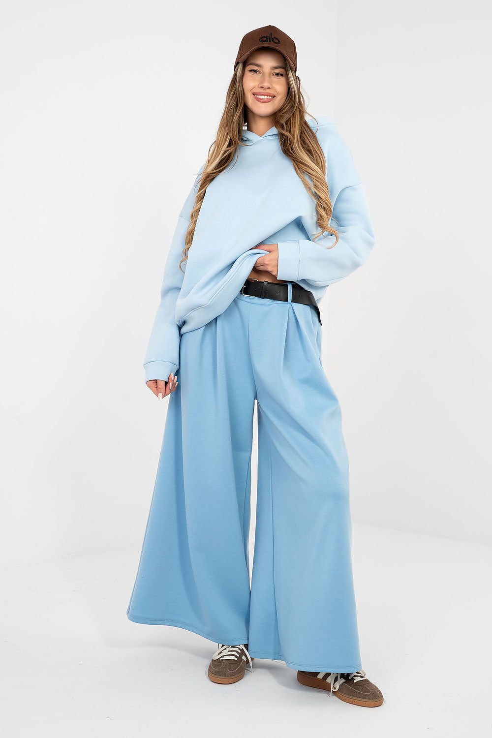 Person wearing a light blue outfit with wide-leg pants on a white background