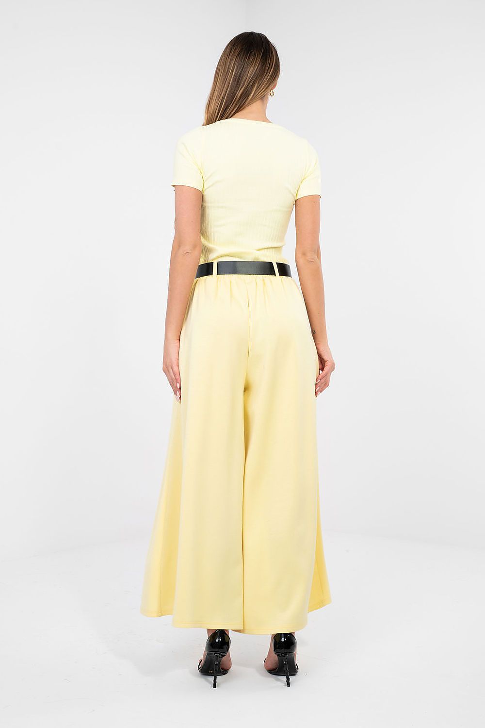 Woman wearing a yellow outfit with a belt on a white background