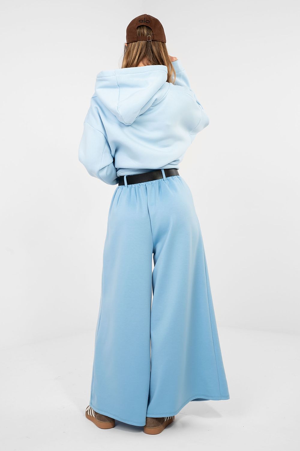 Person wearing a light blue hoodie and wide-leg pants on a white background
