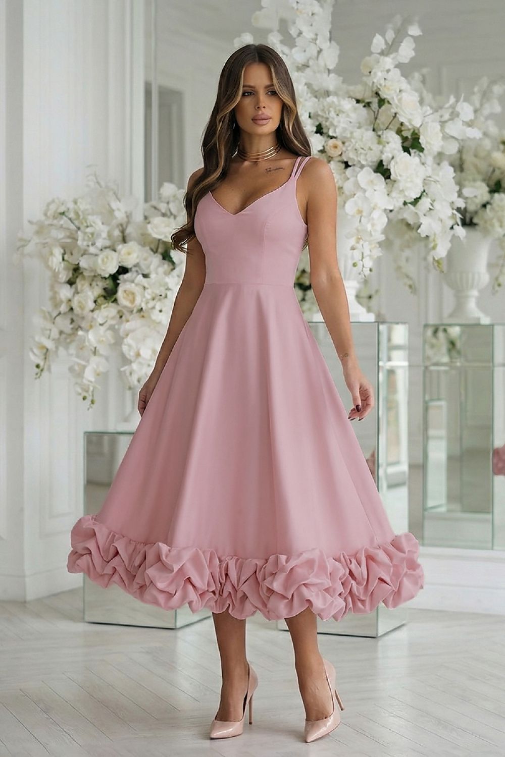 Woman wearing a pink dress with ruffled hem in a decorated room.