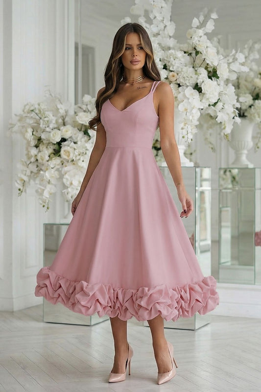 Woman wearing a pink dress with ruffled hem in a decorated room.