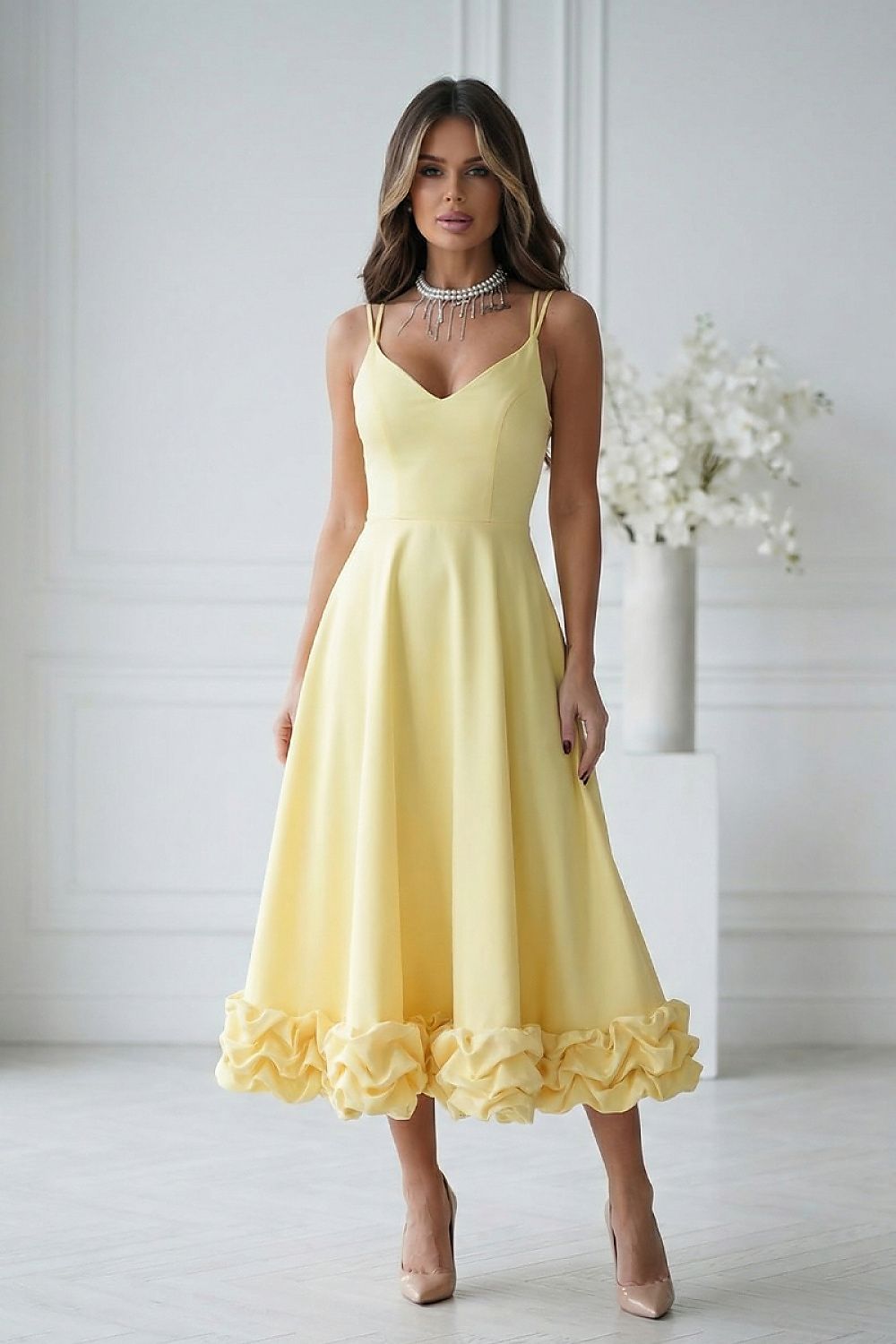 Woman wearing a yellow dress with ruffled hem in a minimalistic setting