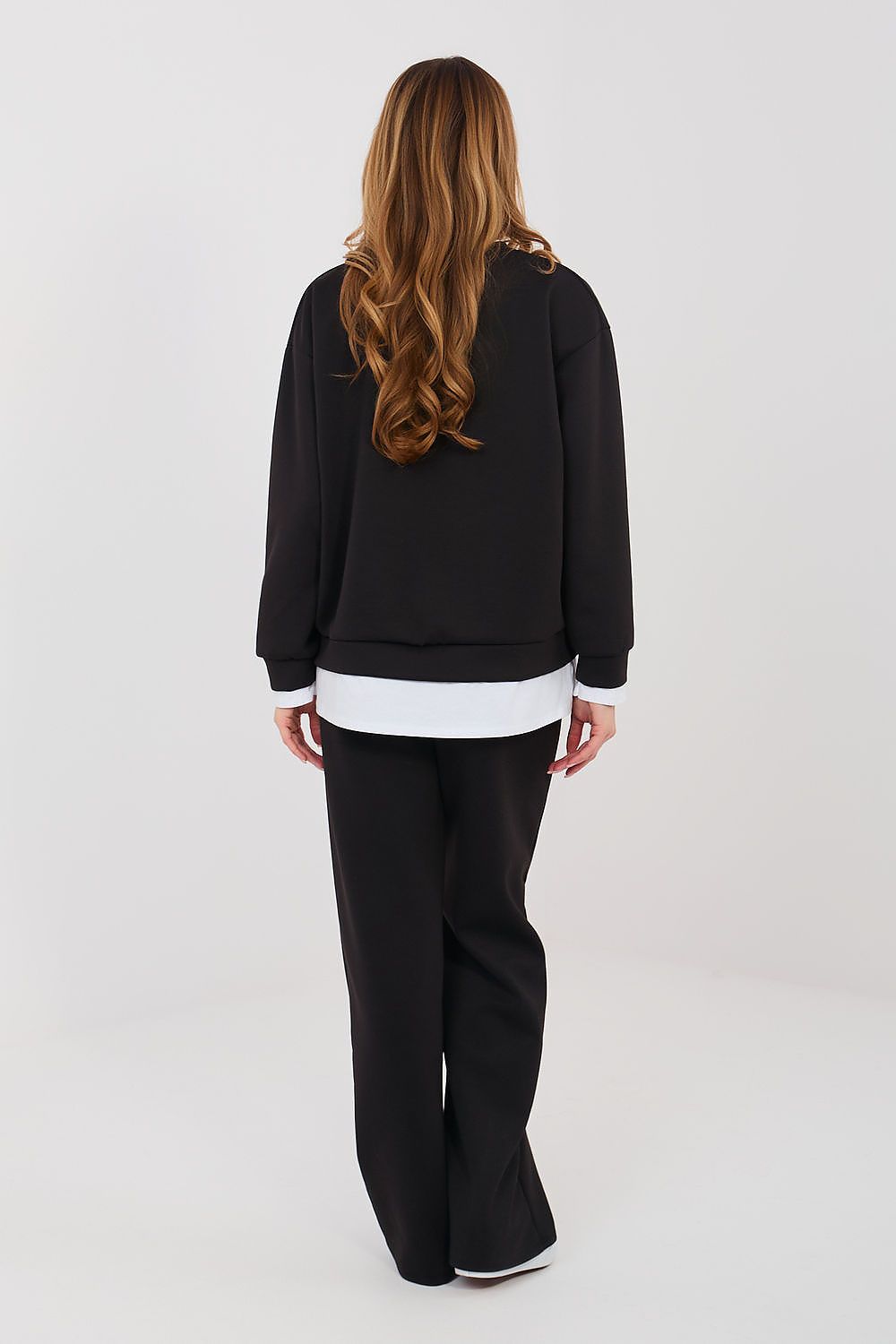 Person wearing a black outfit with a white shirt on a plain background