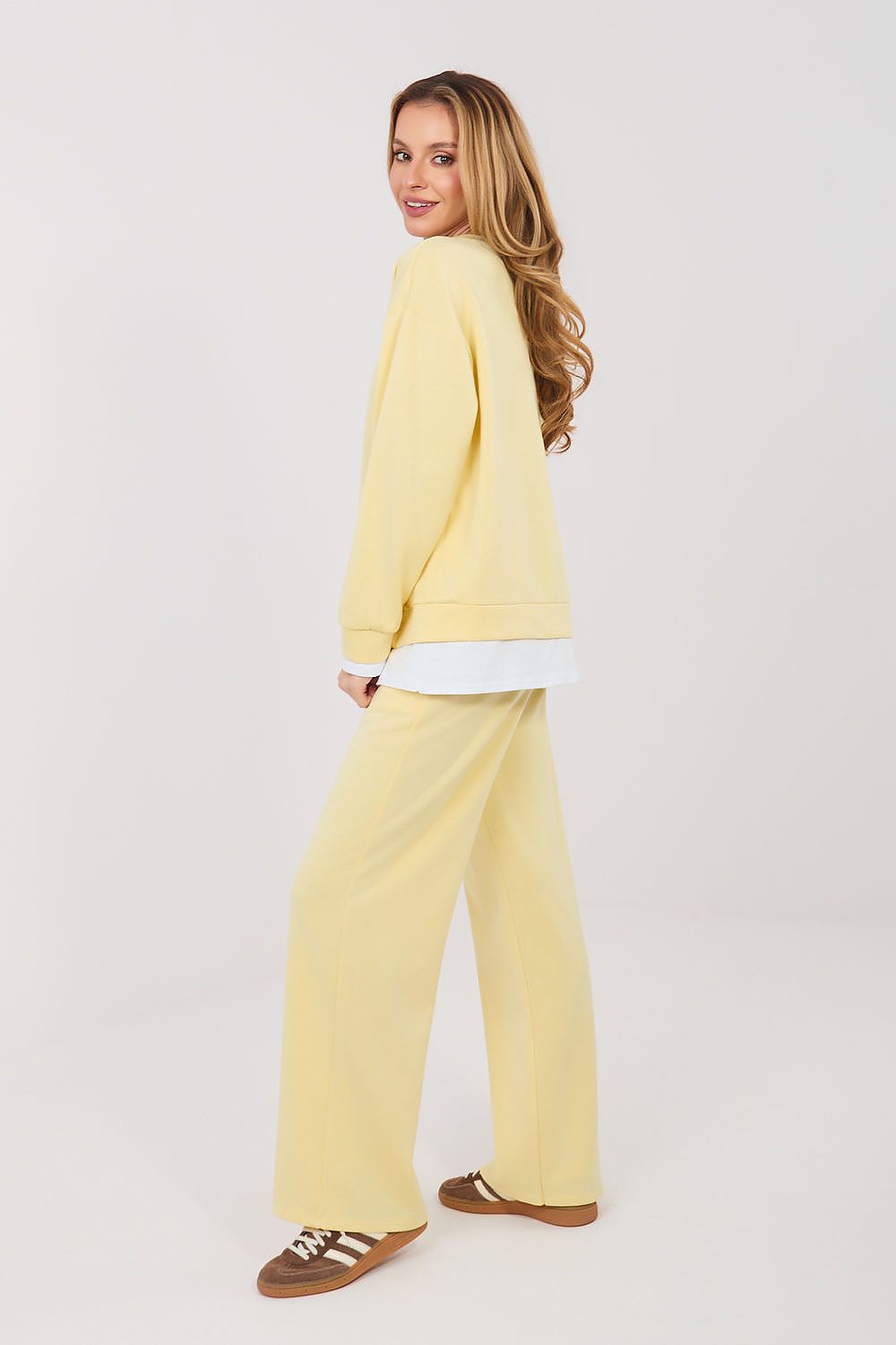 Woman wearing a yellow outfit with a white shirt on a light gray background