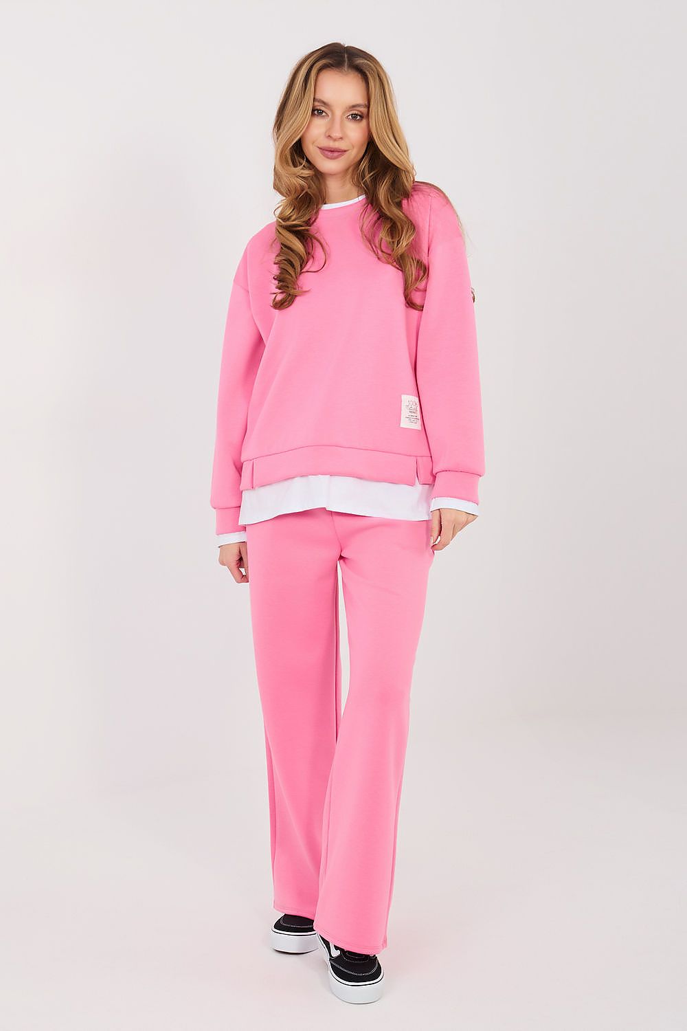 Woman wearing a pink sweatshirt and pants set on a white background